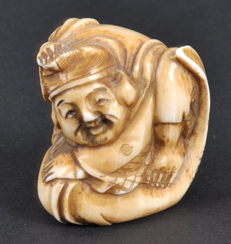 A CARVED IVORY NETSUKE OF A MAN AND CARP. : A CARVED IVORY NETSUKE OF A MAN AND CARP.
