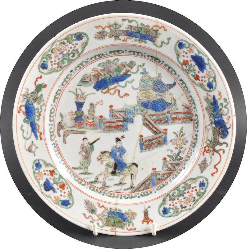 A CHINESE KANGXI PORCELAIN FAMILLE VERTE CIRCULAR P: A CHINESE KANGXI PORCELAIN FAMILLE VERTE CIRCULAR PLATE C1710 painted with figures on horseback. Repaired. 9ins diameter.