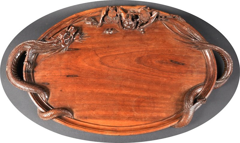 AN UNUSUAL CHINESE QING DYNASTY TWIN HANDLED HARD: AN UNUSUAL CHINESE QING DYNASTY TWIN HANDLED HARDWOOD TRAY modelled with a dragon entwined, the top carved with bats amongst coinage. Minor faults. 2ft 4ins wide.