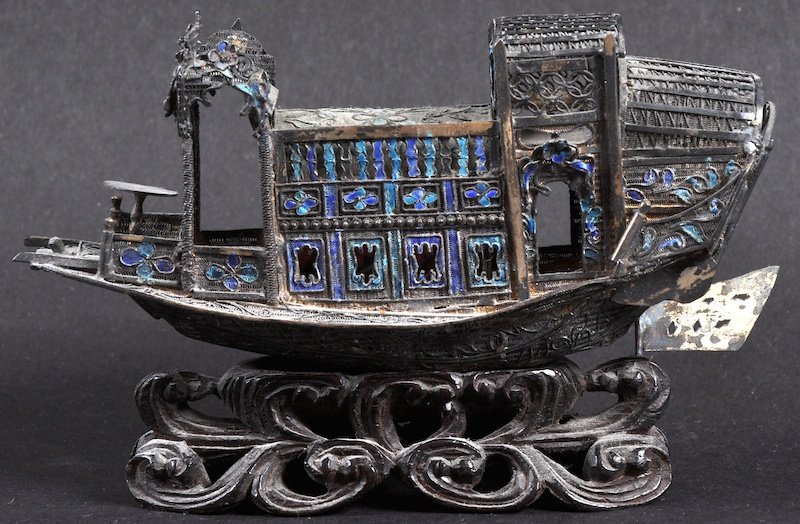 AN EARLY 20TH CENTURY CHINESE SILVER AND ENAMEL NEF mod: AN EARLY 20TH CENTURY CHINESE SILVER AND ENAMEL NEF modelled upon a carved hardwood base. Minor faults. 4.75ins wide.