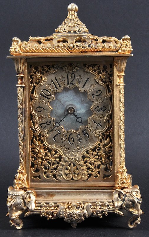 A GILT ISLAMIC STYLE FRENCH BRASS CARRIAGE CLOCK with e: A GILT ISLAMIC STYLE FRENCH BRASS CARRIAGE CLOCK with elephant mounts. 7. 5ins high.