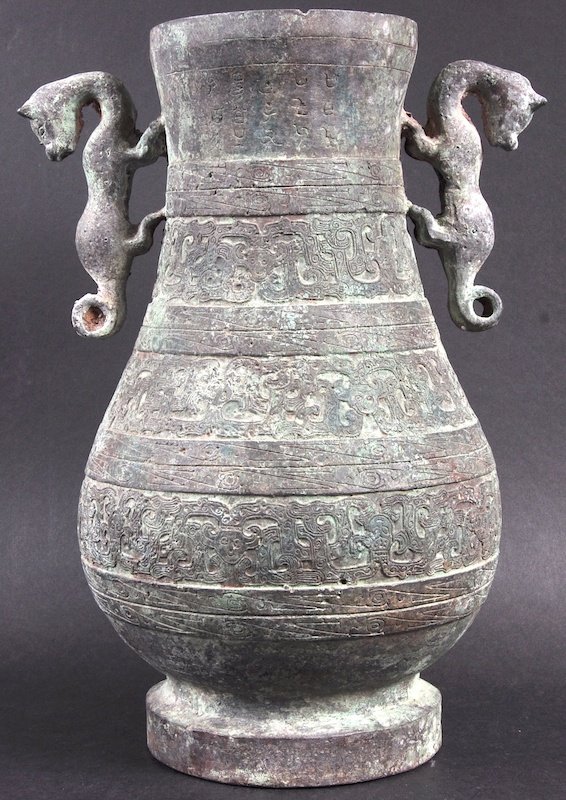 A GOOD EARLY CHINESE ARCHAIC TWIN HANDLED BRONZE VASE p: A GOOD EARLY CHINESE ARCHAIC TWIN HANDLED BRONZE VASE probably Han Dynasty C 206BC – 220 AD, decorated with calligraphy and motifs. Few holes, nick, surface wear. 11.5ins high.