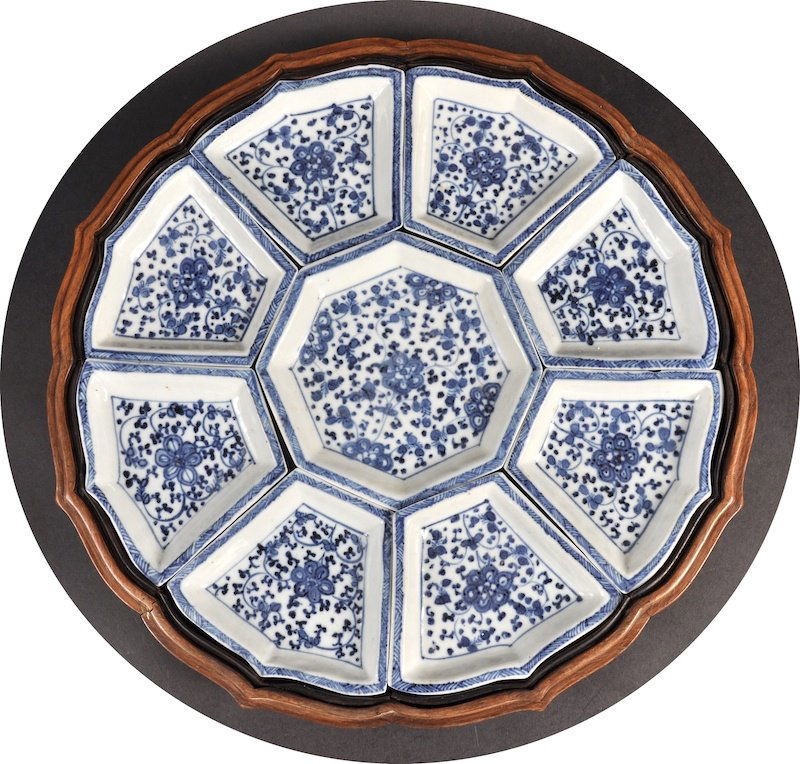 A CHINESE QING DYNASTY BLUE AND WHITE HORDERVES SET con: A CHINESE QING DYNASTY BLUE AND WHITE HORDERVES SET contained within a Chinese hardwood shaped box, painted with flowers. One with tiny chip. 13.5ins diameter.