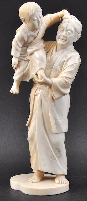 A FINE 19TH CENTURY JAPANESE TOYKO SCHOOL IVORY OKIMONO: A FINE 19TH CENTURY JAPANESE TOYKO SCHOOL IVORY OKIMONO modelled as a male holding aloft a small child, upon a shaped base. Signed. Natural flaws. 10.25ins high.