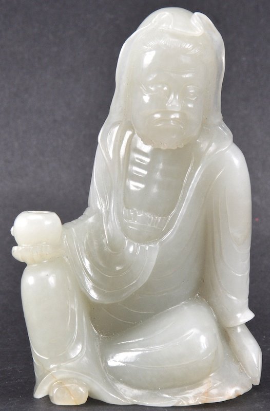 A CHINESE CARVED WHITE JADE FIGURE OF A SEATED SCHOLAR : A CHINESE CARVED WHITE JADE FIGURE OF A SEATED SCHOLAR modelled holding a bowl, with well carved features. Good condition. 3.75ins high.