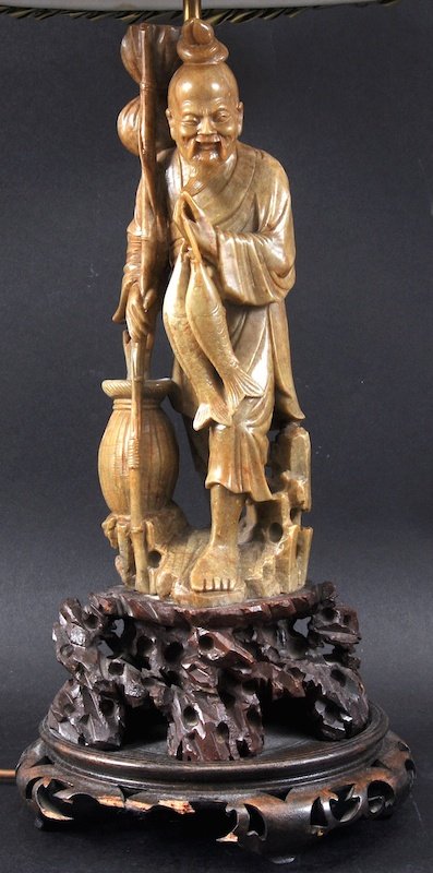 A 19TH CENTURY CHINESE CARVED SOAPSTONE FIGURE OF A FIS: A 19TH CENTURY CHINESE CARVED SOAPSTONE FIGURE OF A FISHERMAN modelled holding his catch upon a rocky outcrop. Figure 12ins high.
