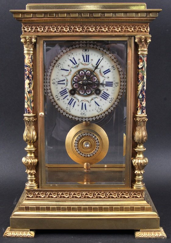 A Good 19th Century French Ormolu And Champleve Enamel: A GOOD 19TH CENTURY FRENCH ORMOLU AND CHAMPLEVE ENAMEL MANTLE CLOCK with enamelled acanthus mounted side columns and crystal encrusted dial. 13.75ins high.