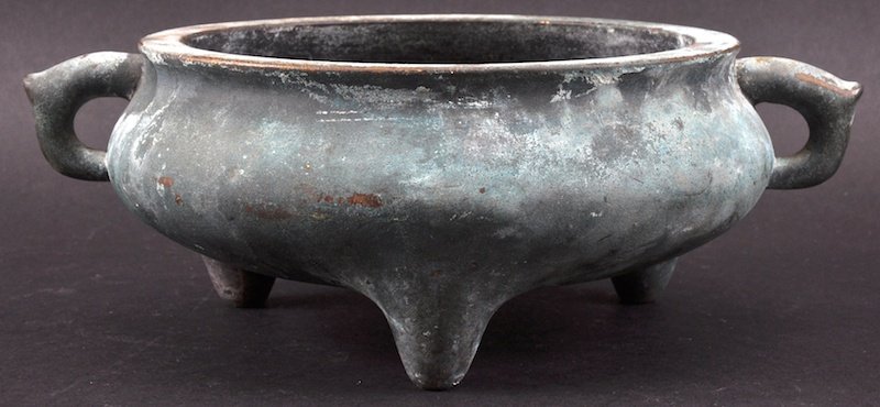 AN 18TH CENTURY CHINESE TWIN HANDLED BRONZE CENSER: AN 18TH CENTURY CHINESE TWIN HANDLED BRONZE CENSER bearing Xuande marks to base, of flattened form, upon three tapering legs. Surface wear. 8ins diameter. Provenance: Private British Collection.