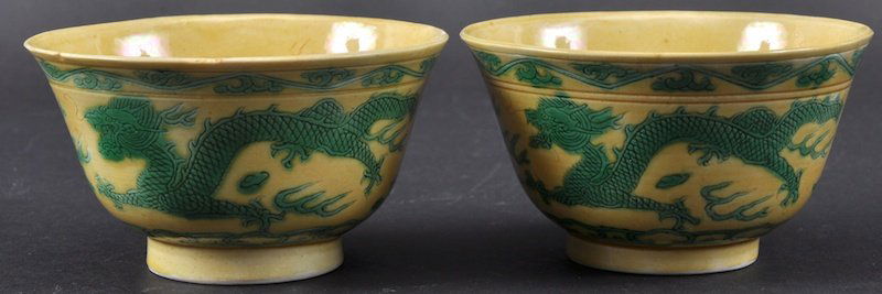 A PAIR OF 19TH CENTURY CHINESE YELLOW GLAZED TEABOWLS: A PAIR OF 19TH CENTURY CHINESE YELLOW GLAZED TEABOWLS Guangxu, bearing Kangxi marks to base, painted with dragons. Minor nicks. 4ins diameter.