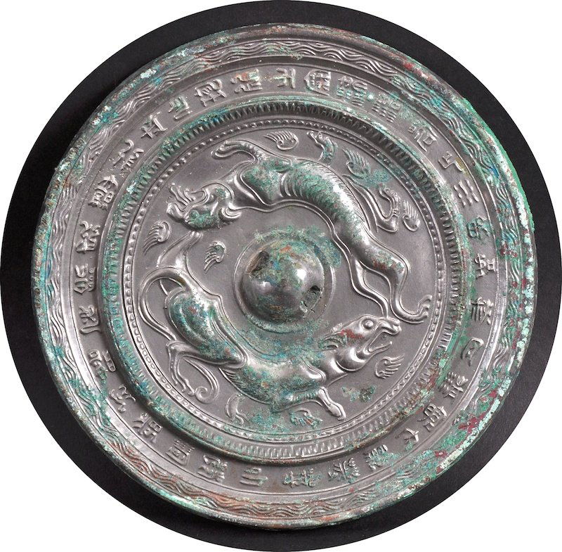 A CHINESE SILVERED BRONZE ARCHAIC STYLE CIRCULAR HAND: A CHINESE SILVERED BRONZE ARCHAIC STYLE CIRCULAR HAND MIRROR decorated with mythical beasts. Surface wear. 6ins diameter.