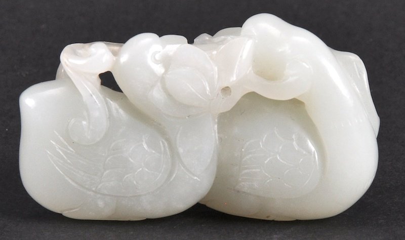 AN 18TH CENTURY CHINESE CARVED WHITE JADE FIGURE: AN 18TH CENTURY CHINESE CARVED WHITE JADE FIGURE Qianlong, depicting two opposing cranes holding a lotus pod. Fissures. 2.25ins wide.