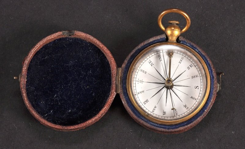 A SMALL POCKET COMPASS, in a leather case.: A SMALL POCKET COMPASS, in a leather case.