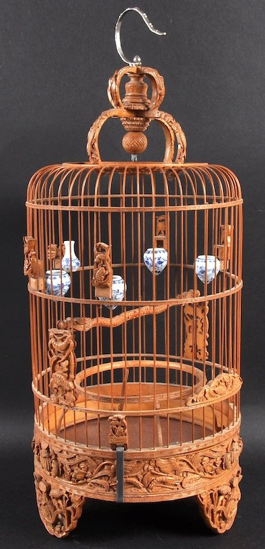 A CHINESE CARVED BAMBOO CYLINDRICAL BIRD CAGE with: A CHINESE CARVED BAMBOO CYLINDRICAL BIRD CAGE with attached blue and white feeding bowls, carved with fish and crustaceans. Minor losses. 20ins high.