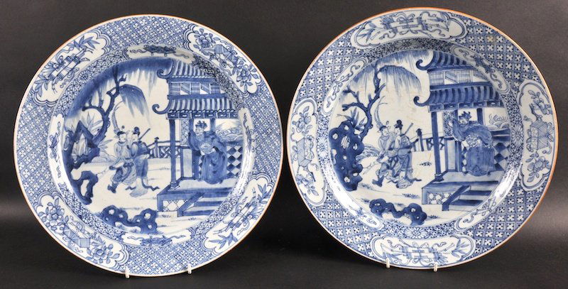 A PAIR OF EARLY 18TH CENTURY CHINESE BLUE AND WHITE: A PAIR OF EARLY 18TH CENTURY CHINESE BLUE AND WHITE CHARGERS Yongzheng, painted with figures standing within a garden of flowering hollow rock. 13.75ins diameter.