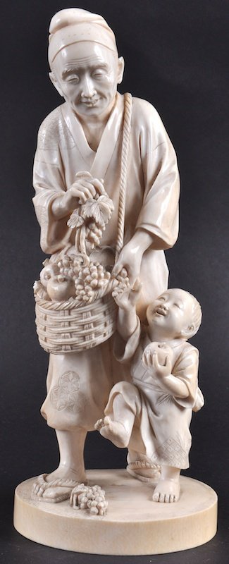 A FINE LATE 19TH CENTURY JAPANESE MEIJI PERIOD TOKYO SC: A FINE LATE 19TH CENTURY JAPANESE MEIJI PERIOD TOKYO SCHOOL OKIMONO depicting a standing father holding a basket of fruit, with a young child his side. Natural flaws. Signed. 11.75ins high.