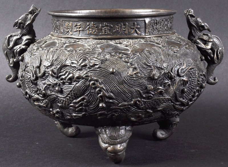 A 19TH CENTURY CHINESE TWIN HANLED BRONZE CENSER: A 19TH CENTURY CHINESE TWIN HANLED BRONZE CENSER bearing Xuande marks to rim, decorated with dragons amongst clouds. Minor wear. 9.5ins diameter.