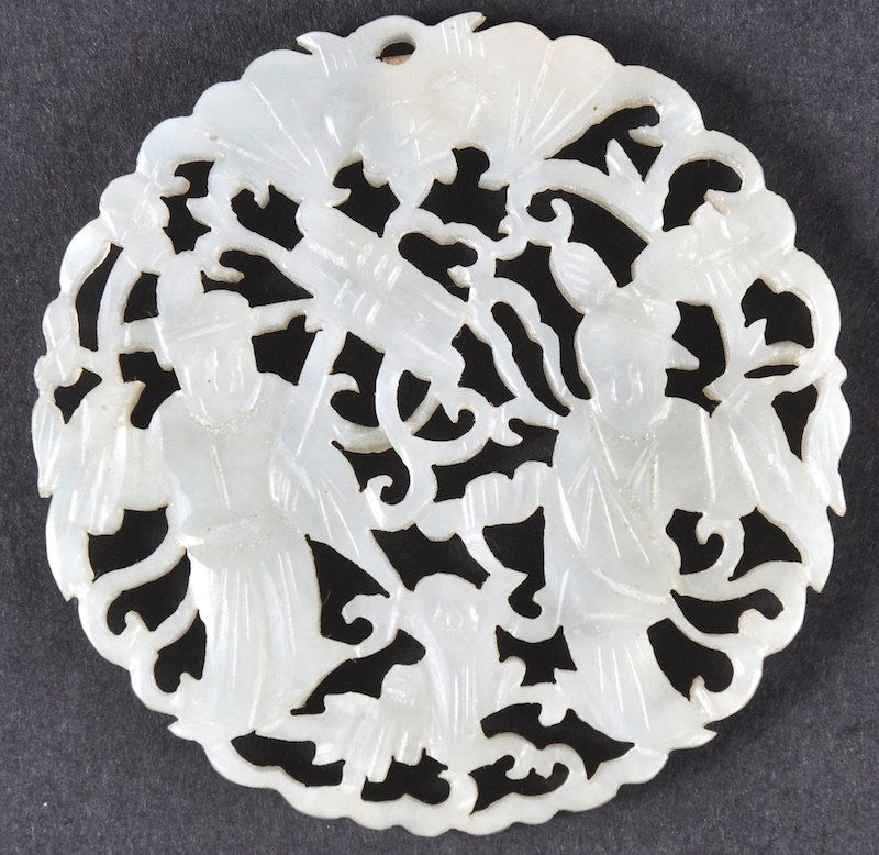 AN 18TH CENTURY CHINESE CARVED WHITE JADE MEDALLION: AN 18TH CENTURY CHINESE CARVED WHITE JADE MEDALLION decorated with two figures amongst scrolling foliage. 2.25ins wide.