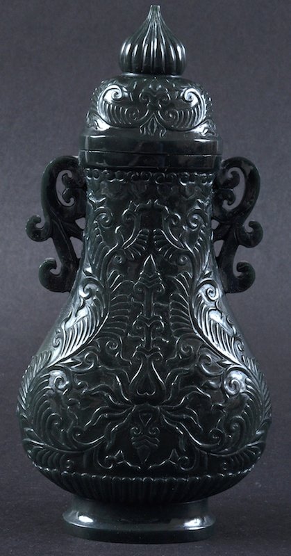 A CHINESE CARVED GREEN JADE MUGHAL STYLE VASE AND COVER: A CHINESE CARVED GREEN JADE MUGHAL STYLE VASE AND COVER decorated with scrolling foliage. Good condition. 8.25ins high.