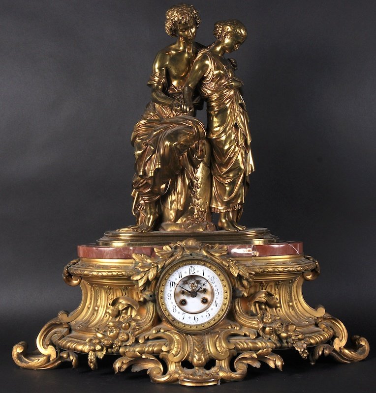 A LARGE 19TH CENTURY FRENCH ORMOLU CLOCK, with two: A LARGE 19TH CENTURY FRENCH ORMOLU CLOCK, with two Classical female figures, standing on a red base. The circular clock and movement with bold scrolls and acanthus. 25 inches high.