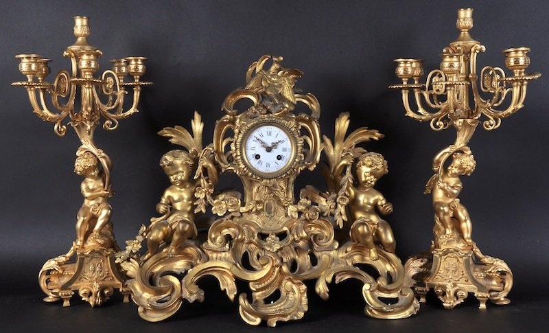 A VERY GOOD EARLY 19TH CENTURY FRENCH ORMOLU THREE: A VERY GOOD EARLY 19TH CENTURY FRENCH ORMOLU THREE PIECE CLOCK GARNITURE, the clock with birds, cupids, garlands, and scrolls. 11 inches high, complete with a pair of candelabra. 21 inches high.