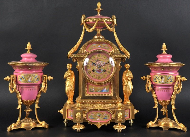 A SUPERB 19TH CENTURY FRENCH ORMOLU AND PORCELAIN THREE: A SUPERB 19TH CENTURY FRENCH ORMOLU AND PORCELAIN THREE PIECE CLOCK GARNITURE, the circular dial by N HORDERINE of France de BRONERS, painted with cupid, surmounted by porcelain lidded urn with classi