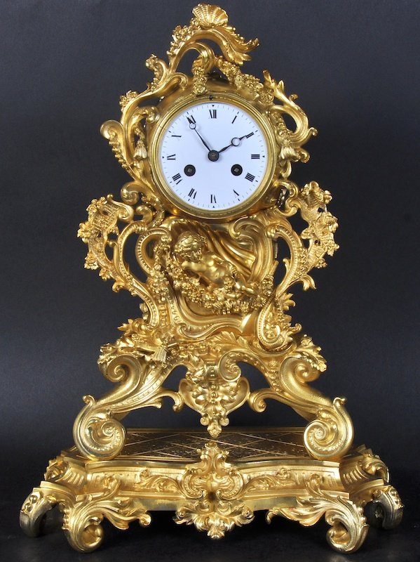 A 19TH CENTURY FRENCH ORMOLU CLOCK, the case with: A 19TH CENTURY FRENCH ORMOLU CLOCK, the case with cupids, scrolls, and tassels. 17 inches high.