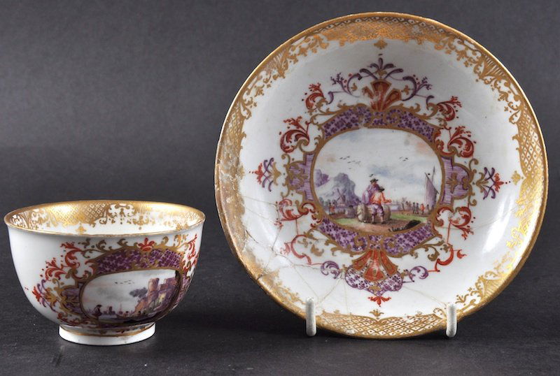 AN 18TH CENTURY MEISSEN TEA BOWL AND SAUCER painted: AN 18TH CENTURY MEISSEN TEA BOWL AND SAUCER painted with panels of costal and harbour scenes (Saucer AF). Provenance: Antique Porcelain Co Ltd. Cross Swords Mark and Gilt No. 93.