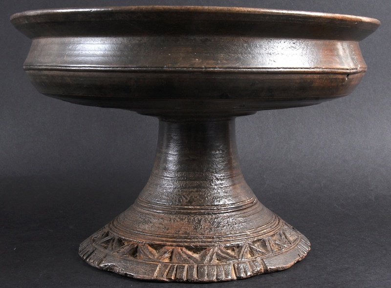 A NATIVE CARVED WOOD CIRCULAR PEDESTAL BOWL with plain: A NATIVE CARVED WOOD CIRCULAR PEDESTAL BOWL with plain bowl and carved base. 13ins diameter.