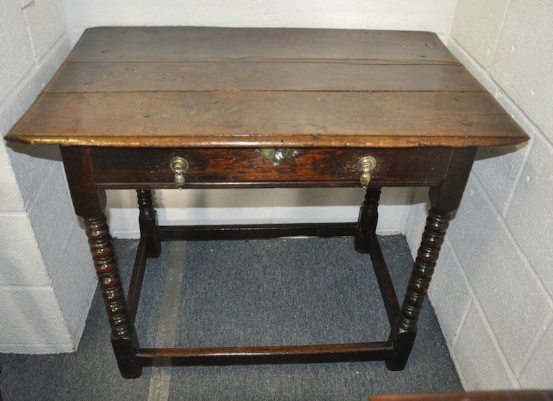 A CHARLES II OAK SIDE TABLE with plank top, single: A CHARLES II OAK SIDE TABLE with plank top, single frieze drawer supported on bobbin turned legs with plain uniting stretcher. Provenance: John Keil, Bath 1985.