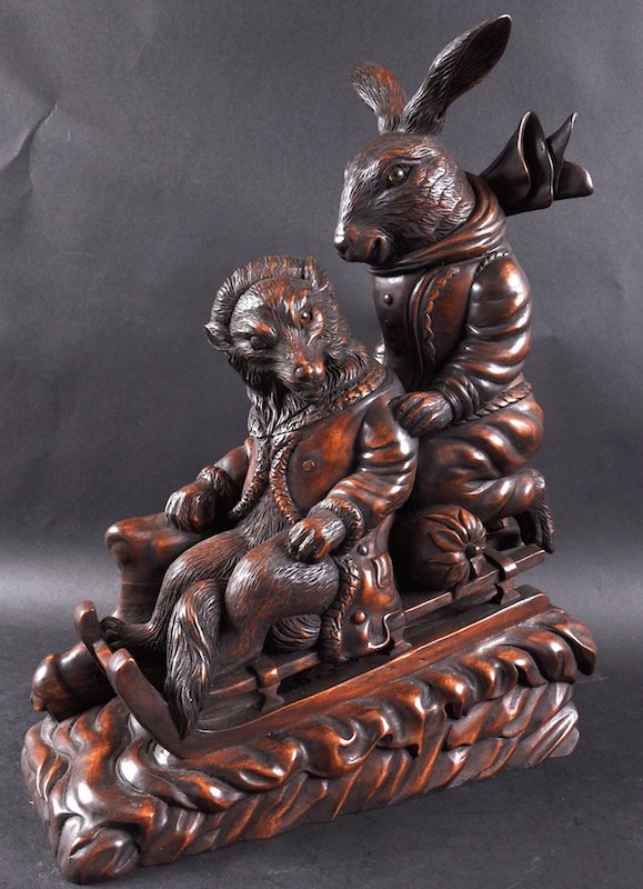 A BLACK FOREST DESIGN CARVED WOOD BOX as a rabbit and a: A BLACK FOREST DESIGN CARVED WOOD BOX as a rabbit and a fox on a sleigh. 19ins high.