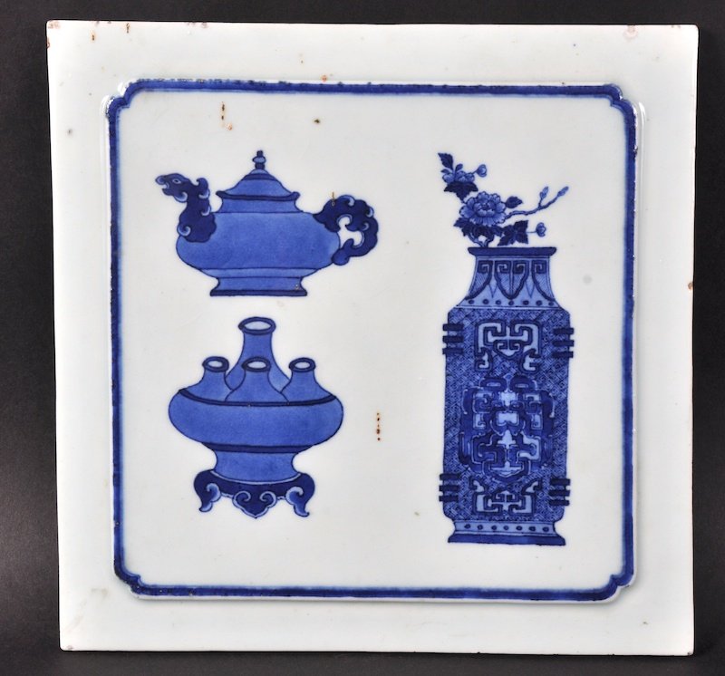 AN 18TH/19TH CENTURY CHINESE BLUE AND WHITE SQUARE TILE: AN 18TH/19TH CENTURY CHINESE BLUE AND WHITE SQUARE TILE painted with precious objects. Firing flaw to rim. 9. 5ins square.