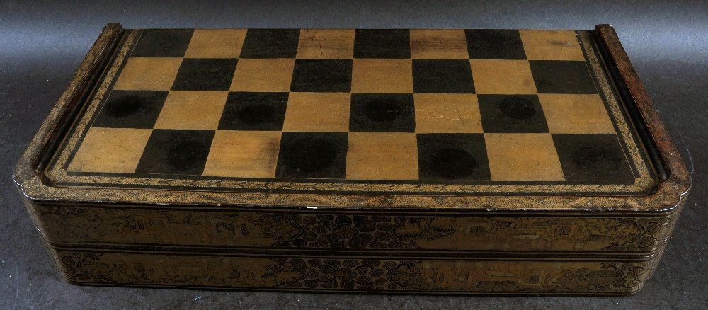 A CHINESE EXPORT LACQUERED WOOD CHESS & BACKGAMMON: A CHINESE EXPORT LACQUERED WOOD CHESS & BACKGAMMON FOLDING LACQUERED WOOD BOX, containing a sectional Indian ivory chess set, the box 16.5in x 8.25in x 3.25in, the largest chess piece 3.75in high.
