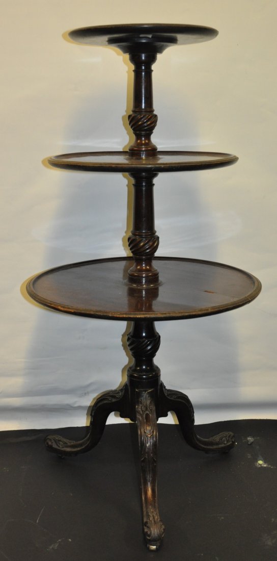 A SMALL GEORGIAN MAHOGANY THREE TIER CIRCULAR DUMB: A SMALL GEORGIAN MAHOGANY THREE TIER CIRCULAR DUMB WAITER with turned centre column and carved tripod base. 3ft 4ins high. £80-150.
