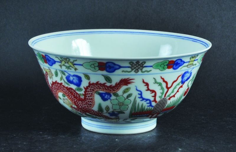 A CHINESE WUCAI DRAGON & PHOENIX PORCELAIN BOWL, the: A CHINESE WUCAI DRAGON & PHOENIX PORCELAIN BOWL, the sides painted with alternating dragon and phoenix beneath a narrow border of ribboned emblems, the base with a Qianlong seal mark, 6.2in diameter.