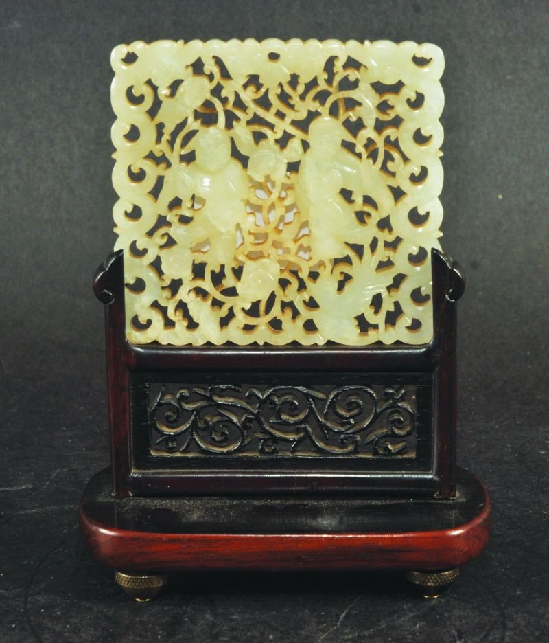 A SMALL CHINESE 19TH/20TH CENTURY CARVED JADE TABLE: A SMALL CHINESE 19TH/20TH CENTURY CARVED JADE TABLE SCREEN, together with a fitted carved wood stand, the jade pierced and carved with scene of the He He Erxian, the twins enclosed by dense scrolling 