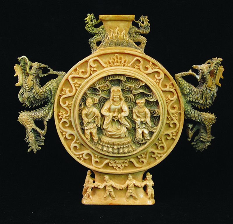A CHINESE 20TH CENTURY CHINESE CARVED AND STAINED IVORY: A CHINESE 20TH CENTURY CHINESE CARVED AND STAINED IVORY MOON VASE, each side centred by a figural panel, the sides and also the neck with double dragon handles, the base with an archaic mark, 5.25in h