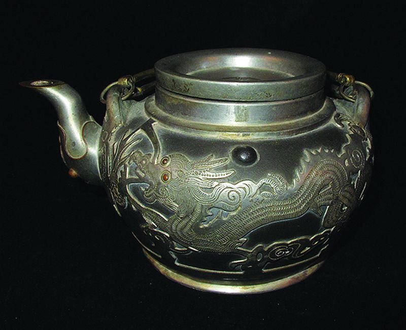 AN EARLY 20TH CENTURY CHINESE PEWTER-CASED YIXING: AN EARLY 20TH CENTURY CHINESE PEWTER-CASED YIXING POTTERY TEAPOT & COVER, the sides decorated on the pewter with dragons, the base with an impressed mark, 7in long & 3.9in high. £80-120