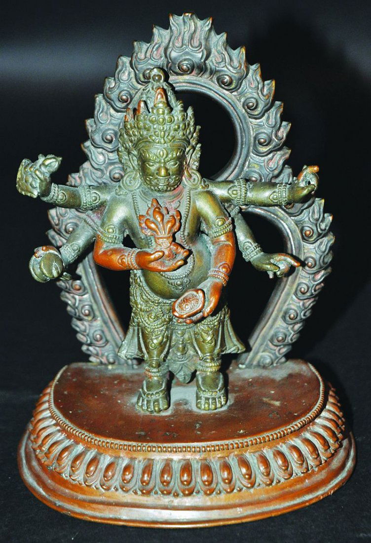 A 19TH CENTURY TIBETAN OR NEPALESE SECTIONAL BRONZE: A 19TH CENTURY TIBETAN OR NEPALESE SECTIONAL BRONZE MODEL, of a multi-armed deity standing on a lotus base before a flaming aureole, 7in high overall. £300-500
