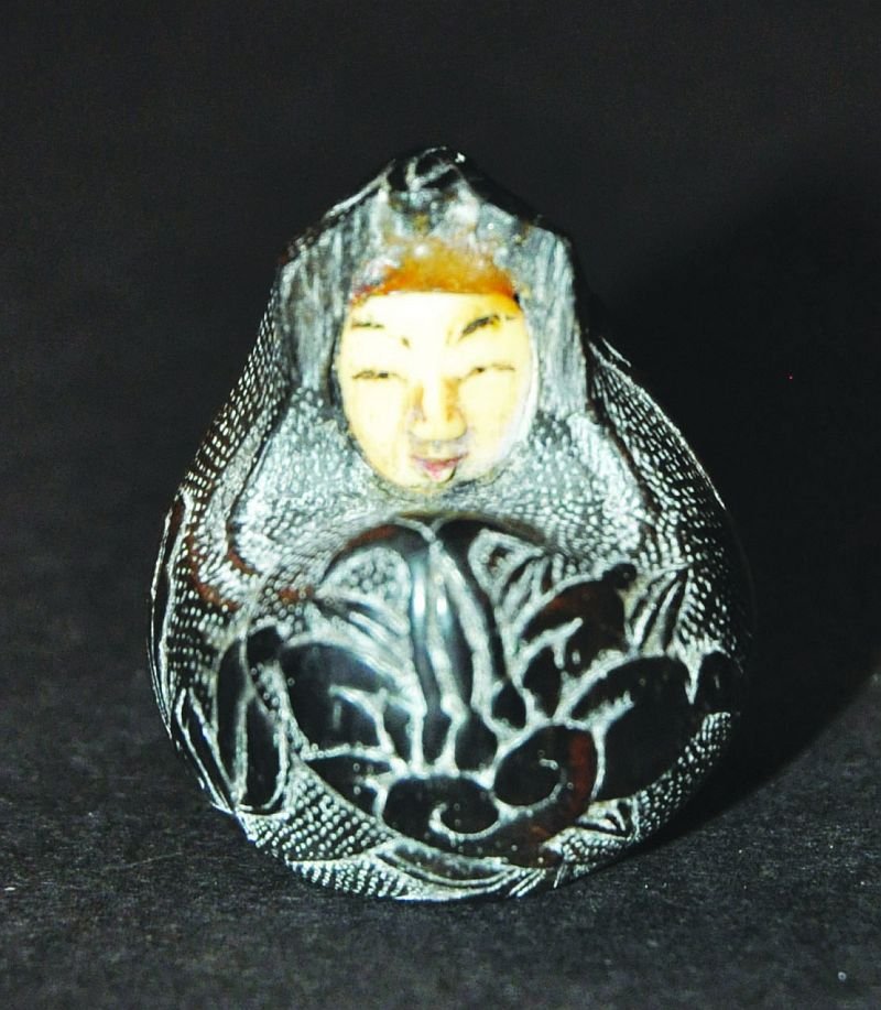 A JAPANESE CARVED WOOD NETSUKE OF DARUMA, circa 1900,: A JAPANESE CARVED WOOD NETSUKE OF DARUMA, circa 1900, his cloak carved in low relief with flowers and leafage, his face inlaid in ivory, 1.4in high. £80-120