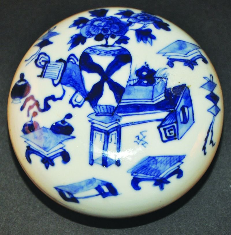A CHINESE BLUE & WHITE PORCELAIN BOX & COVER, circa: A CHINESE BLUE & WHITE PORCELAIN BOX & COVER, circa 1900, the cover painted with stands and various objects, the base with a four-character Kangxi mark, 3.6in diameter. £40-60