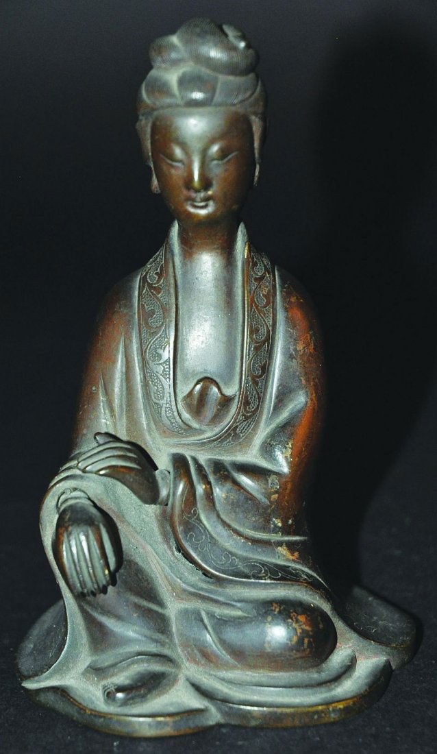 A GOOD 18TH CENTURY CHINESE BRONZE FIGURE OF GUANYIN,: A GOOD 18TH CENTURY CHINESE BRONZE FIGURE OF GUANYIN, the Goddess seated with one knee upraised, the head elegantly modelled, the robes with engraved foliate scroll borders, 6in high. £300-400