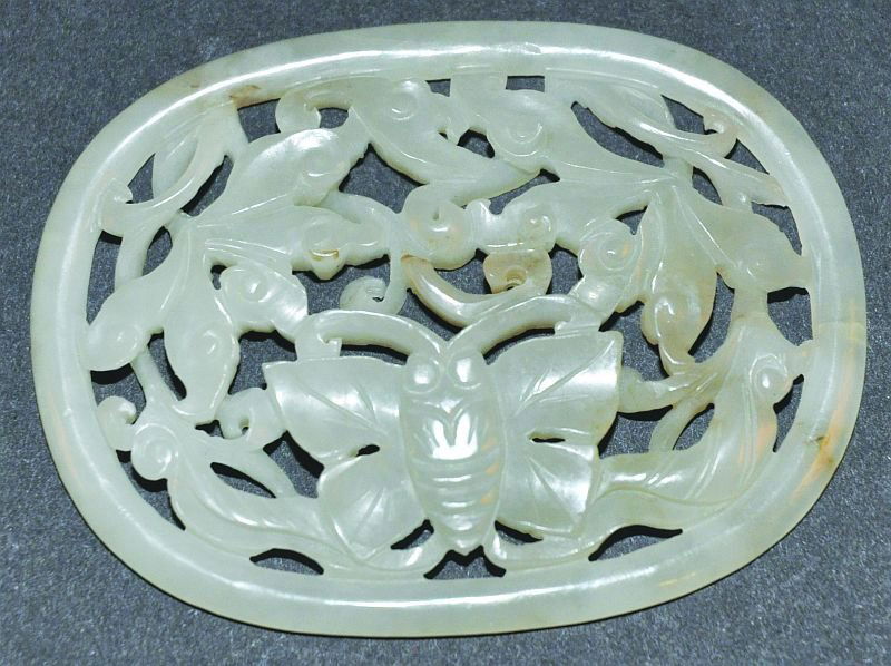 A SMALL 19TH/20TH CENTURY CHINESE CARVED & PIERCED OVAL: A SMALL 19TH/20TH CENTURY CHINESE CARVED & PIERCED OVAL JADE PLAQUE, decorated with a butterfly and lotus, 2.6in wide x 1.9in high. £50-70