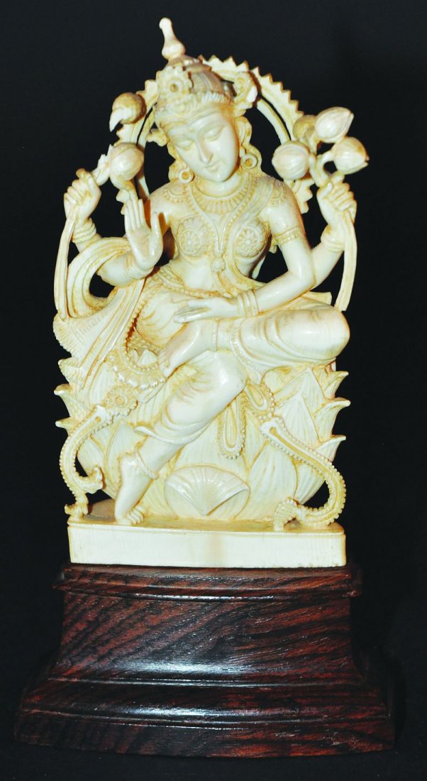 A GOOD QUALITY 19TH CENTURY INDIAN CARVED IVORY FIGURE: A GOOD QUALITY 19TH CENTURY INDIAN CARVED IVORY FIGURE OF LAKSHMI, seated on a lotus throne, the whole upon a fixed wood base, 6.9in high overall, the ivory 5.1in high. £100-150
