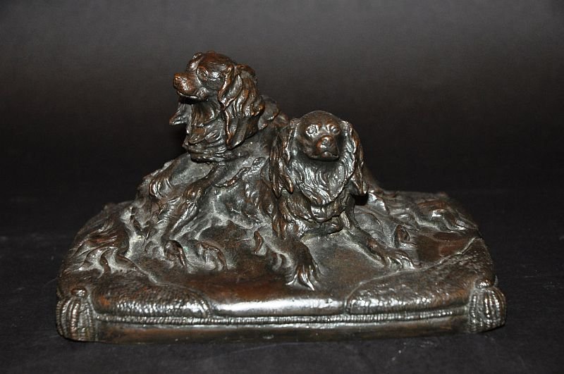 A BRONZE GROUP OF TWO KING CHARLES SPANIELS ON A: A BRONZE GROUP OF TWO KING CHARLES SPANIELS ON A CUSHION. 8ins long. £80-120.