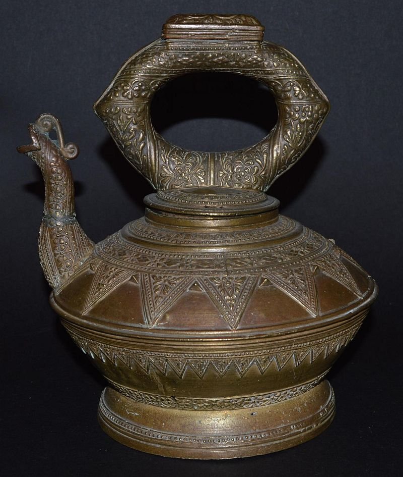 A BRONZE CIRCULAR WATER KETTLE, SUMATRA, with unusual: A BRONZE CIRCULAR WATER KETTLE, SUMATRA, with unusual opening on the handle and grotesque spout, LATE 19TH CENTURY. 9ins high. £50-80.