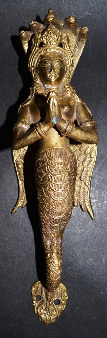 A TIBETAN OR NEPALESE CAST BRASS DOOR HANDLE of a: A TIBETAN OR NEPALESE CAST BRASS DOOR HANDLE of a winged APSARA, NEPAL OR TIBET, MID 20TH CENTURY. 10.5ins high. £30-50.
