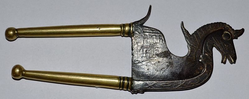 A BALINESE HORSE SHAPED BETEL CUTTER (KACIP), iron: A BALINESE HORSE SHAPED BETEL CUTTER (KACIP), iron inlaid with brass with a HINDU SWASTIKA MOTIF and brass handles, INDONESIA, 19TH CENTURY. 7ins long. £25-50.