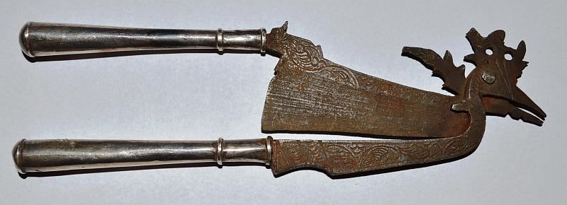 A MALAYSIAN OR INDONESIAN BETEL CUTTER (KACIP) with: A MALAYSIAN OR INDONESIAN BETEL CUTTER (KACIP) with iron and silver handles. 6.25ins long. £25-50.