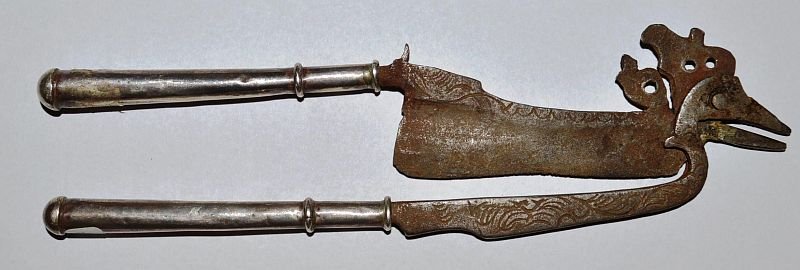 A MALAYSIAN OR INDONESIAN BETEL CUTTER (KACIP), iron: A MALAYSIAN OR INDONESIAN BETEL CUTTER (KACIP), iron with silver handles. 7ins long. £25-50.