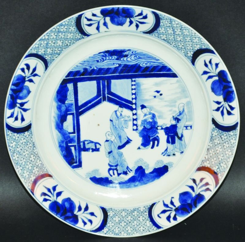 A CHINESE KANGXI MARK & PERIOD BLUE & WHITE PORCELAIN: A CHINESE KANGXI MARK & PERIOD BLUE & WHITE PORCELAIN PLATE, circa 1700, the interior painted to its centre with a dignitary and attendants in a terrace setting, the rim with repeated panels of pomegr